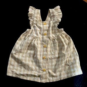 A beautiful button up gingham dress with ruffle trimmings on straps